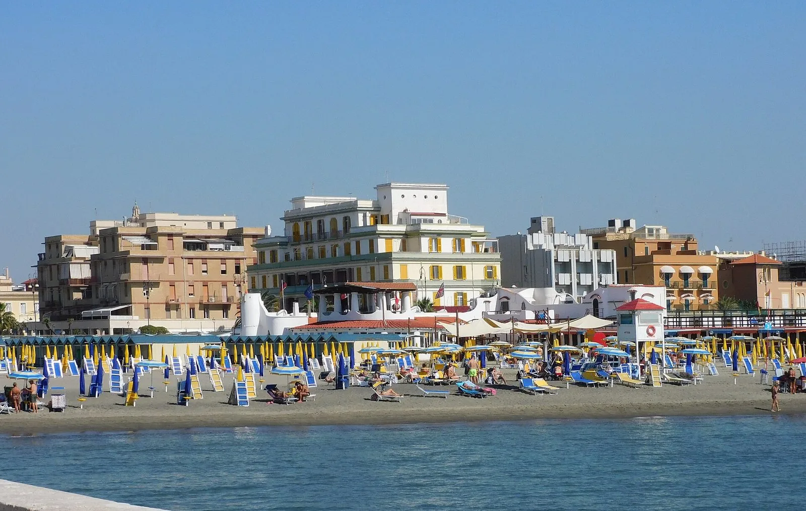 Spiaggia di Lido di Ostia d'estate con ombrelloni e palazzi del lungomare